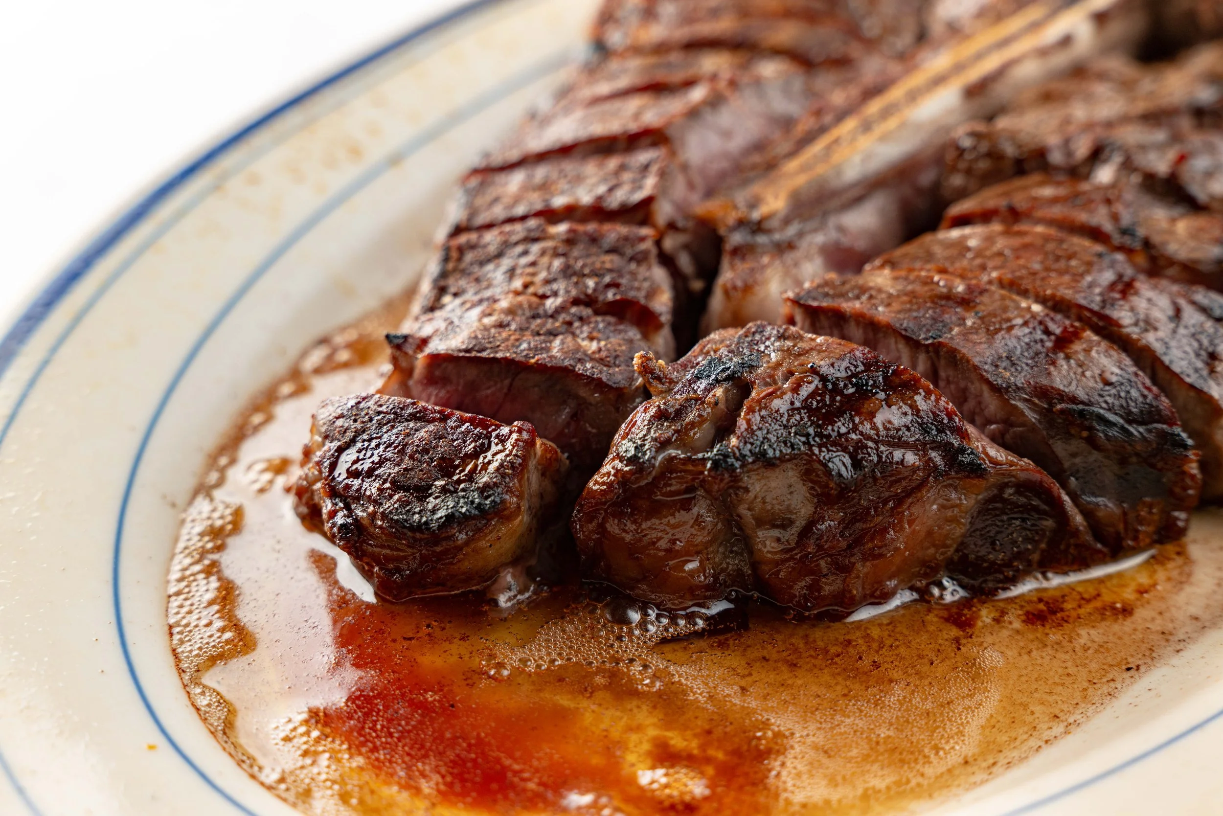 Sliced steak on a white plate with jus